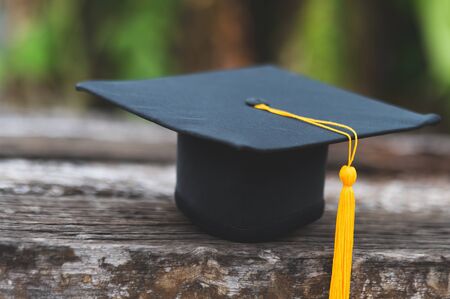 Black graduates hat and yellow tassels pasted on old woodの写真素材