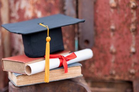 Black graduates hat and yellow tassel place an old bookの写真素材