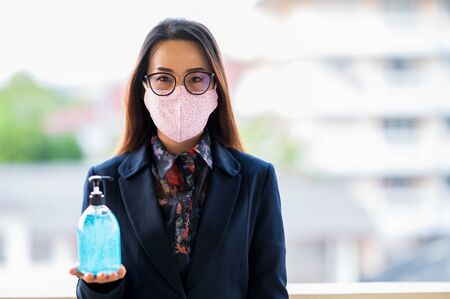 Working women wear sanitary masks, wash hands with alcohol gel to prevent virusesの写真素材