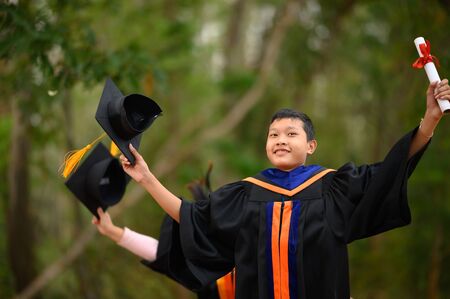 Asian students wore black frilly suits, black hats, yellow tassels on graduation day.の写真素材