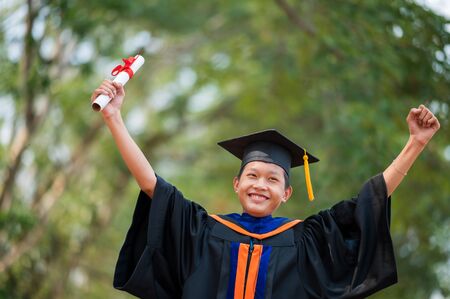 Asian students wore black frilly suits, black hats, yellow tassels on graduation day.の写真素材