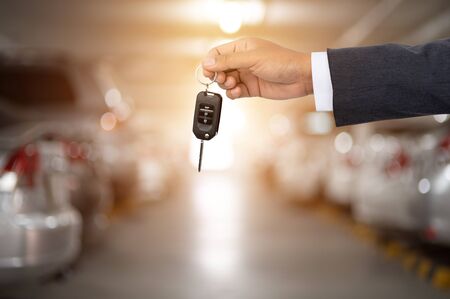 A business man with a car key on the back of a parking lotの写真素材