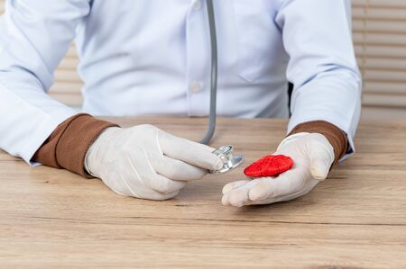 Hand doctor hold Stethoscope and red heart pace on the desk,Heart disease concept.の写真素材