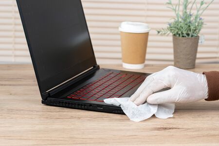 Men wear white gloves, use alcohol and spay cloth to clean their laptops to prevent viruses.の写真素材