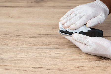 Men wear white gloves, use alcohol-free cloths and spills to clean their mobile phones to prevent...
