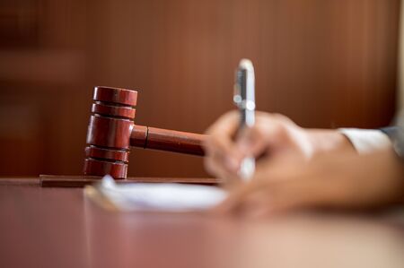 The lawyer is carrying a pen to write a case record in the courtroomの写真素材