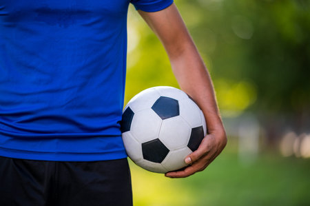 closeup of a soccer football player wearing blue team holding black and white soccer football with...