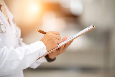 The doctor used a pen to write a diagnosis for the patient.の写真素材
