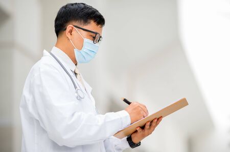 The doctor used a pen to write a diagnosis for the patient.の写真素材