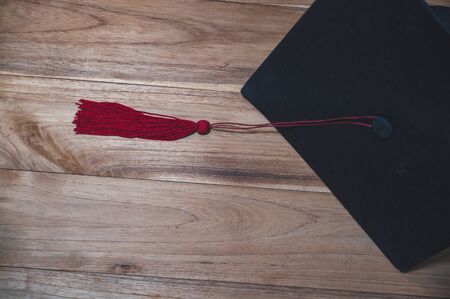 Black university graduate hat placed on a wooden floorの写真素材