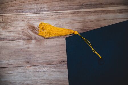 Black university graduate hat placed on a wooden floorの写真素材