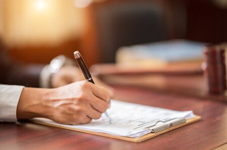 The lawyer is carrying a pen to write a case record in the courtroomの写真素材