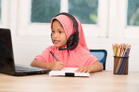 Back to school concept,Muslim girls studying online at home To reduce social distance and prevent communicable diseasesの写真素材