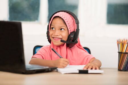 Back to school concept,Muslim girls studying online at home To reduce social distance and prevent communicable diseasesの写真素材