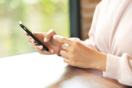 Woman wearing surgical mask in cafe shopping online with Mobile Phoneの写真素材