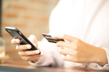 Woman wearing surgical mask in cafe shopping online with Mobile Phone