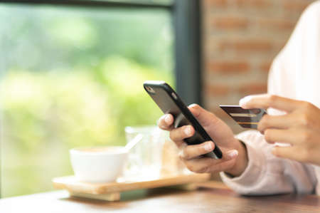 Woman wearing surgical mask in cafe shopping online with Mobile Phoneの写真素材