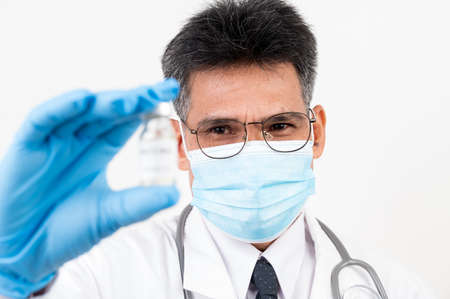 Portrait Male doctor holding a syringe and vaccine bottle with isolated backgroundの写真素材