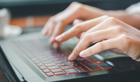 Close up of female hands typing on laptop computer at officeの写真素材