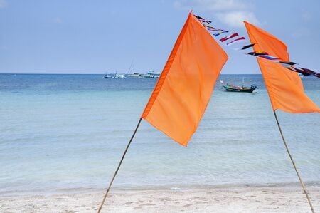 flags against blue sky, sea and boatの写真素材