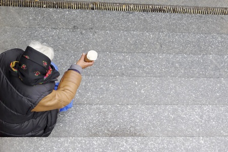 Social issues, old homeless woman begs on underground steps  With copyspace のeditorial素材