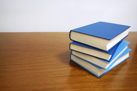 Books stack on a wooden desk table with blank empty cover and copyspace.の写真素材