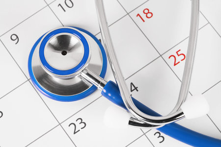 A close-up view of a stethoscope on a calendar page, medical concept of planning doctor appointment and medical check-ups.の写真素材