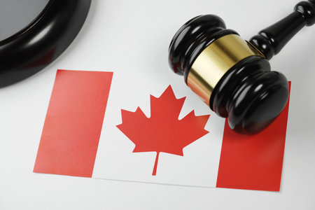 Canada law, legal system and justice concept with a wooden judge gavel and the Canadian flag on a white desk.の写真素材