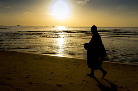 Monk on Hua Hin beach with silhouetteの写真素材