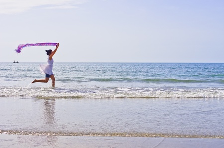 Woman ran a cloth held outdoors on the beach.の写真素材