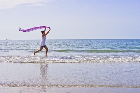 Woman ran a cloth held outdoors on the beach.の写真素材