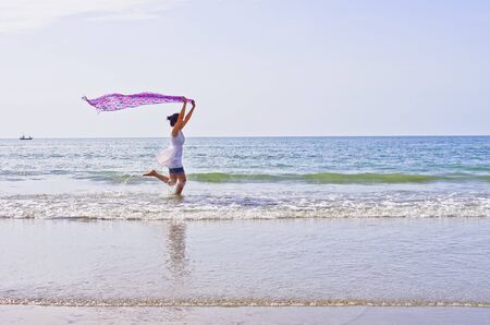 Woman ran a cloth held outdoors on the beach.の写真素材