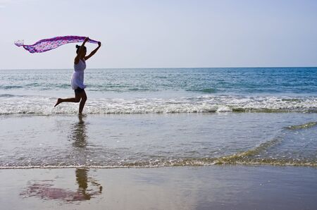 Woman ran a cloth held outdoors on the beach.の写真素材