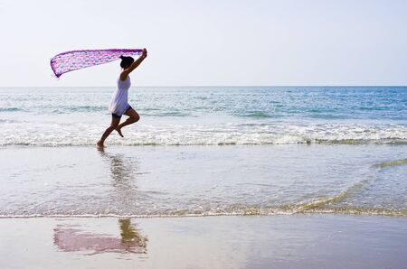 Woman ran a cloth held outdoors on the beach.の写真素材