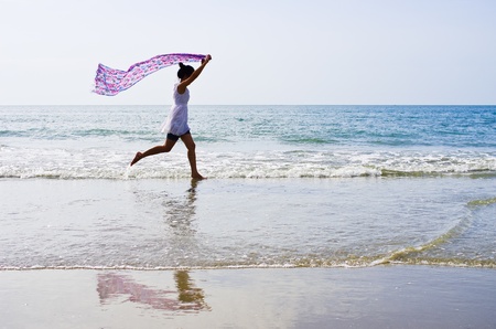 Woman ran a cloth held outdoors on the beach.の写真素材
