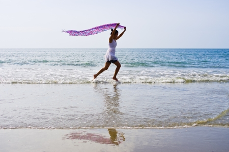 Woman ran a cloth held outdoors on the beach.の写真素材