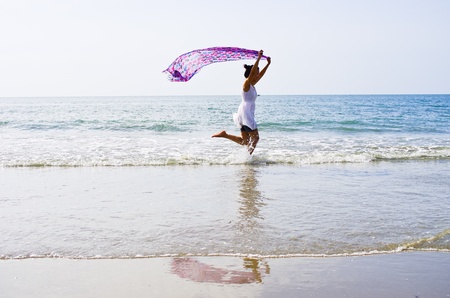 Woman ran a cloth held outdoors on the beach.の写真素材