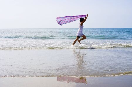 Woman ran a cloth held outdoors on the beach.の写真素材