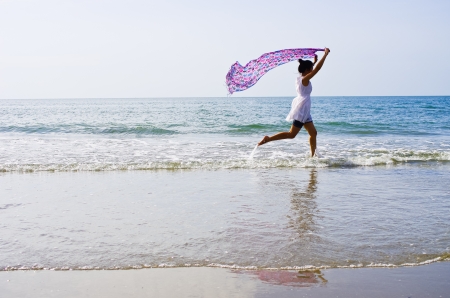 Woman ran a cloth held outdoors on the beach.の写真素材