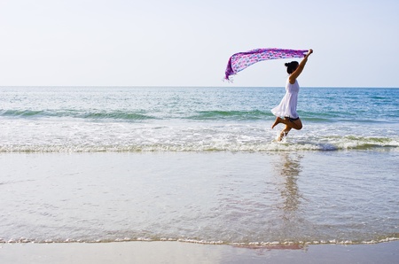 Woman ran a cloth held outdoors on the beach.の写真素材