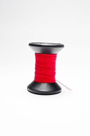 The red thread wrapped in black thread isolated on white backgroundの写真素材