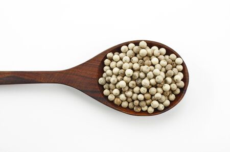 Pepper seeds in wooden spoon. Isolated on white.の写真素材