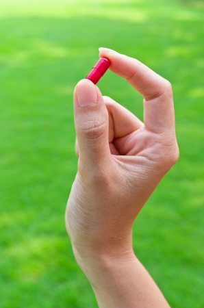 Red pills in the hands of women  Set against the green grass の写真素材