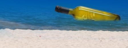 Wine bottle with ship inside lying on the beach. Conceptual imageの写真素材