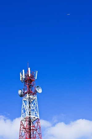 Telecommunications tower, painted white and red in a day of clear blue sky.