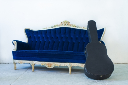 Vintage luxury Blue sofa Armchair and guitar case in white room.の写真素材