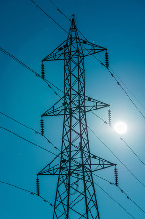 High voltage towers at night with the moon.