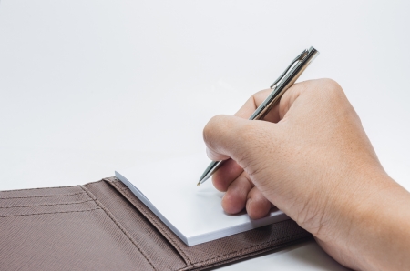 pen in hand writing on the notebook  isolated on whiteの写真素材