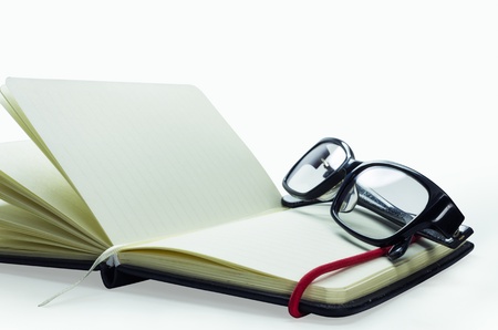 black frame glasses on the notebook, Isolated on white. Business concept.の写真素材