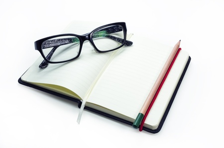Pencil and black frame glasses on the notebook, Isolated on white. Business concept.の写真素材